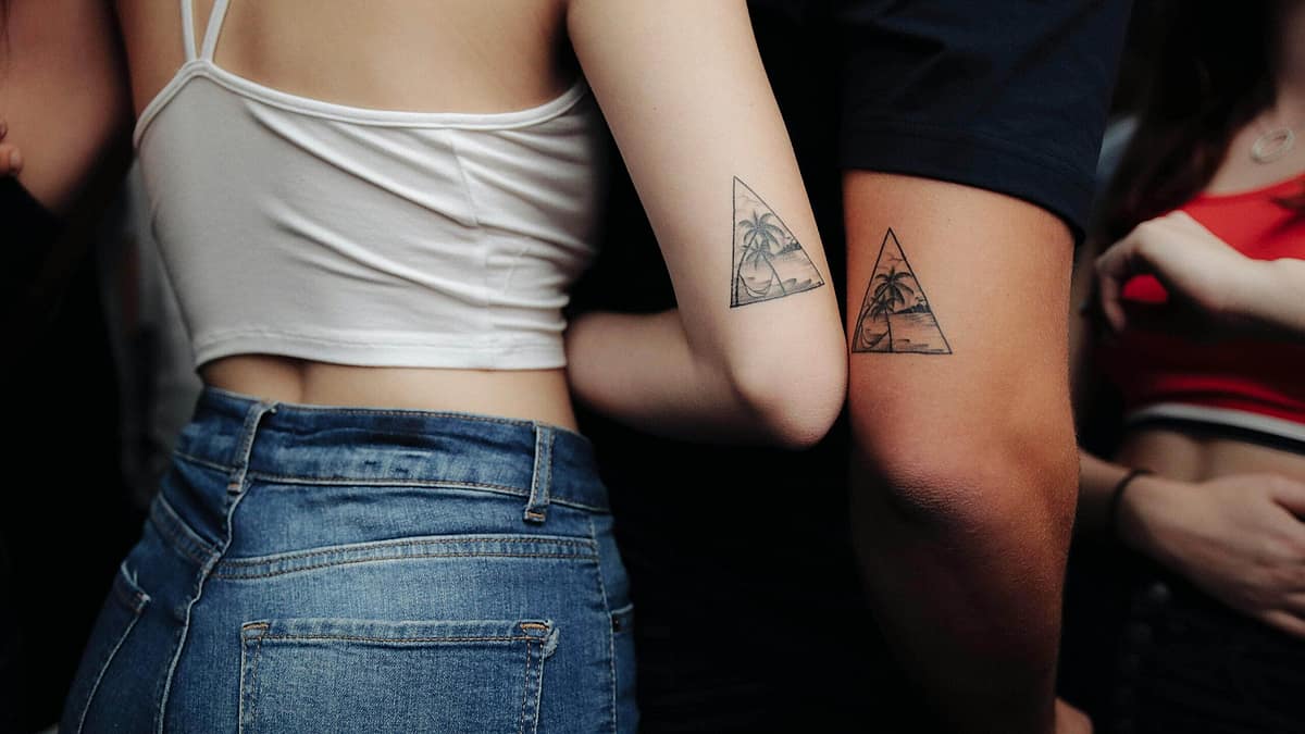 Two friends comparing small matching tattoos on their arms