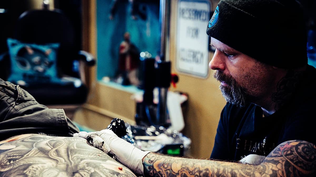 Mentor guiding an apprentice through tattoo machine setup
