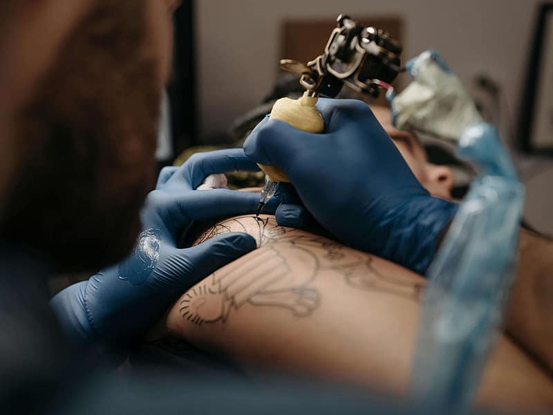 Tattoo artist layering colour during a complex cover-up
