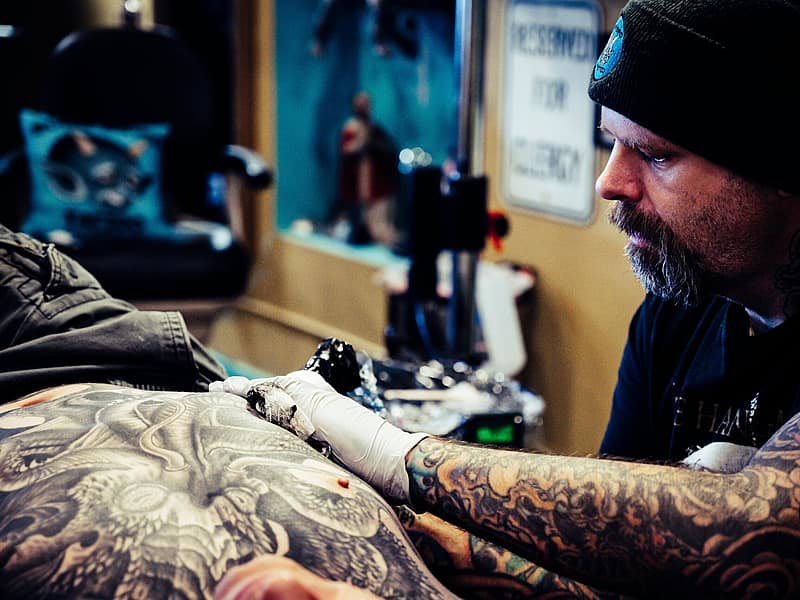 Mentor guiding an apprentice through tattoo machine setup